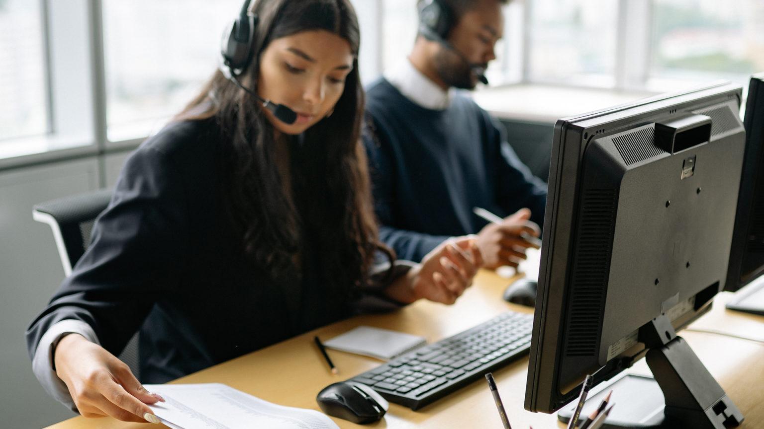 Support professionals wearing headsets working at their computers